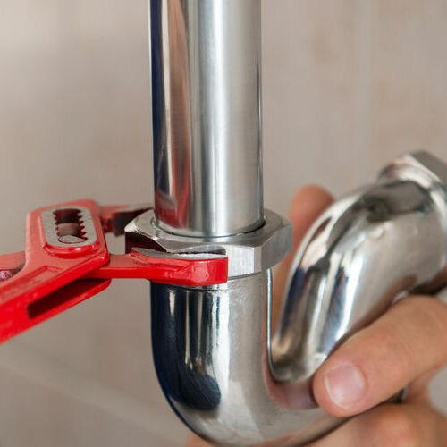 closeup of plumber fixing pipe with wrench